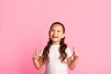 Şuraya bak. Tatlı Asyalı çocuk parmaklarını fotokopi odasına uzatıyor. Mor renkli stüdyo duvarına, afişe.