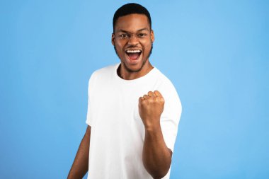 Zaferin sevinci. Afrikalı Adam, Mavi Arkaplan Üzerindeki Başarıyı Kutluyor Hareketi 'ni yapıyor. Stüdyo Çekimi