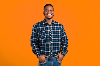 Siyah milenyum adamı kameraya gülümsüyor, el ele tutuşuyor, sarı arka planda poz veriyor. Stüdyo Çekimi