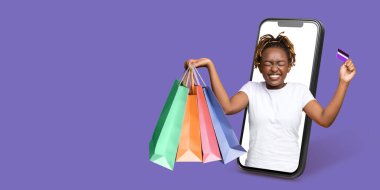 Alıcı, akıllı telefon kullanarak internetten alışveriş yapıyor. Bir elinde alışveriş torbaları tutuyor ve son alışverişlerinin heyecanını canlı bir ortamda gösteriyor..