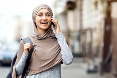 Şehre yürürken telefonda konuşan tesettürlü heyecanlı kız, boş yer.
