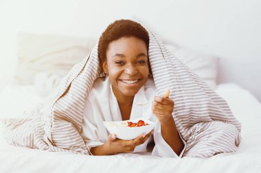 Sabahları sağlıklı yiyecekler. Mutlu Afrikalı Amerikalı kız kahvaltı yapıyor, salata yiyor, güneş parlıyor, boş yer var.