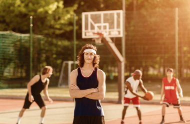 Gülümseyen basketbolcu ve takımının açık hava sahasında oynadığı portre.