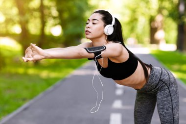 Parkta koşmadan önce ısınan güzel Koreli kız, dışarıda koşmanın tadını çıkar, boş alan.