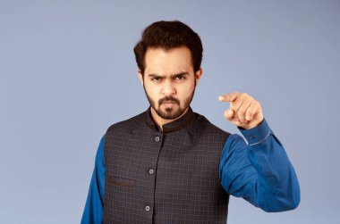 Öfkeli Hintli adam menekşe arka planda suçlamalarla ekranı işaret ediyor.