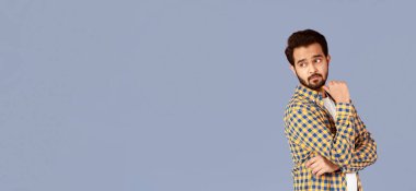 Boş alanda arkasını kollayan düşünceli Hintli adam, leylak arkaplan. Panorama