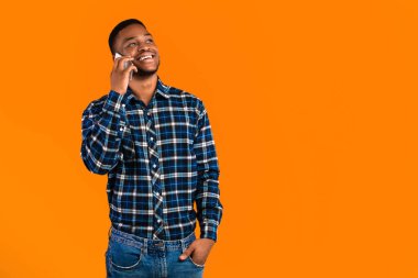 Sarı arka planda cep telefonu pozu veren Afro-Amerikalı adam konuşuyor. Telefon Çağrısı Konsepti. Stüdyo Çekimi, Boş Alan