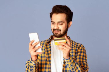 Cep telefonu ve kredi kartıyla online alışveriş yapan mutlu Hintli adam.