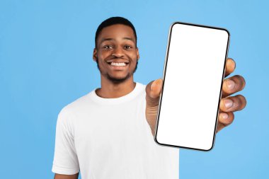 İlk olarak. Siyah adam bir numarayı gösteriyor. Mavi arka planda kameraya gülümsüyor. Stüdyo Çekimi