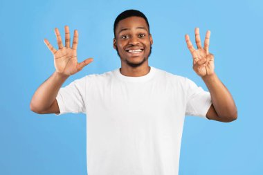 Siyah Adam Mavi Arkaplanda Ayakta Duran Parmaklarıyla Sekiz Numara Gösteriyor. Stüdyo Çekimi