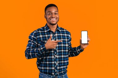 Neşeli Afrikalı Adam Sarı Stüdyo Arkaplanında Duran Akıllı Telefon Boş Ekran Gösteriyor. Harika Mobil Uygulama. Model