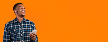 Sarı arka planda duran kulaklıkları kullanarak cep telefonuyla konuşan mutlu Afrikalı Amerikalı adam. Stüdyo Çekimi