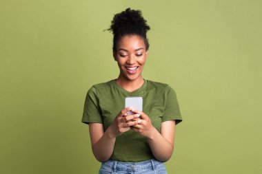 Harika bir uygulama. Yeşil stüdyo duvarında akıllı telefon kullanan mutlu zenci kadın portresi