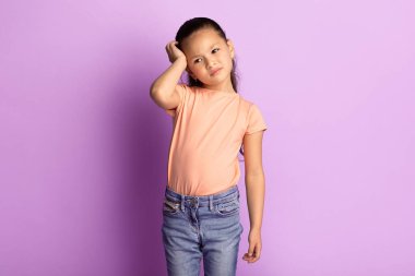 Baş ağrısı ve migren. Asyalı üzgün ve sıkılmış bir çocuğun portresi. Kafasına elle dokunuyor, çalışmaktan yoruluyor. Üzgün kız, Pastel Mor Stüdyo 'nun arka planında izole edilmiş. Hayal kırıklığı ve sorun.