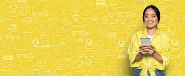 Alıcı, akıllı telefonundan online alışveriş için mobil bir uygulama ile iletişime geçiyor. Canlı sarı arka planda teslimat ve ticaretle ilgili ikonlar yer alıyor ve alışveriş deneyimine ekleniyor.