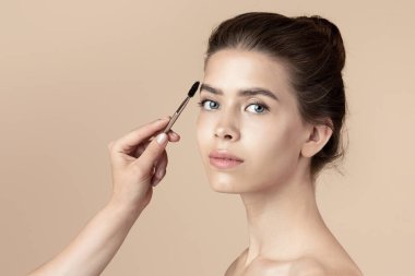 Makyöz, genç kızların yüzüne maskara sürüyor. Yüzü bej rengine bürünmüş.