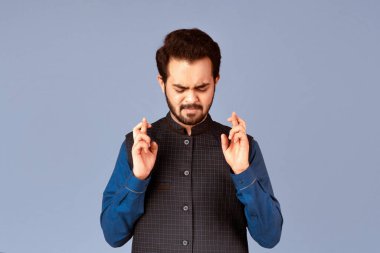 Dilek tutuyorum. Batıl inançlı Hintli bir adamın portresi parmaklarını menekşe arkaplan ve panorama üzerinde çapraz tutuyor.