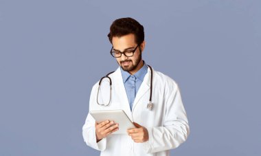 Çevrimiçi doktor danışmanlığı. Tablet bilgisayarlı yakışıklı Hintli doktor internette müşteriyle eflatun hakkında konuşuyor. Panorama