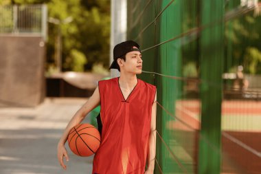 Sahada topu olan düşünceli, genç Asyalı basketbolcu, kopya alanı. Milenyum sporcusu maçtan sonra dinleniyor, turnuvaya hazırlanıyor. Profesyonel spor konsepti