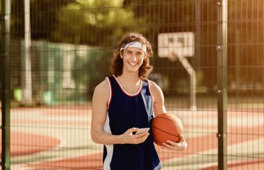 Dışarıda cep telefonuyla gülümseyen milenyum basketbolcusu.