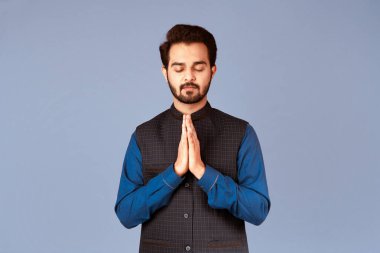 Sakin Hintli adam dua ediyor ya da menekşe arka planı üzerinde meditasyon yapıyor. Panorama