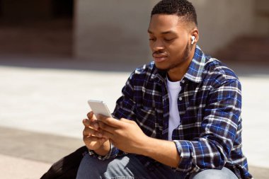 İnternete göz atıyorum. Kentte oturan kendinden emin afro öğrenci, müzik dinliyor ve akıllı telefon cihazında SMS yazıyor.