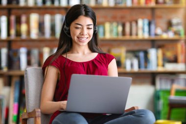 Gülümseyen Asyalı öğrenci, kafede dizüstü bilgisayarda oturup, rahat koltukta oturup Uzay 'ı kopyalıyor.