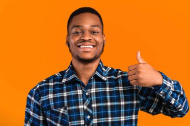 Pozitif Afrikalı Adam, Sarı Arkaplan 'ın üzerinde duran Kameraya Gülümseyen Bir Şey Onaylıyor. Hoşuma gitti. Stüdyo Çekimi