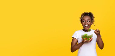 Taze salatalı neşeli Afrikalı kadın fotokopi odasına bakıyor sarı stüdyo arka planı, panorama