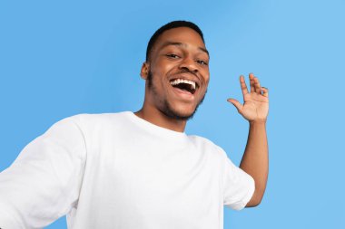 - Selam. Pozitif Siyah Adam Selfie Çekiyor Mavi Stüdyo Arkaplanında El Poz Veriyor, Kameraya Gülümsüyor