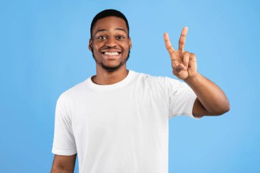 Afrikalı Adam Mavi Stüdyo Arkaplanda İki Numaralı Poz Gösteriyor, Kameraya Gülümsüyor. Sen İkinci Kavramsın.