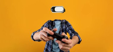 Bir kişi aktif olarak sanal gerçeklik gözlüğü ve yüzü ya da yüzü olmayan bir oyun denetleyicisi kullanır, parlak sarı bir arka plana karşı kurulmuştur. Odaklanmamız gereken şey,.