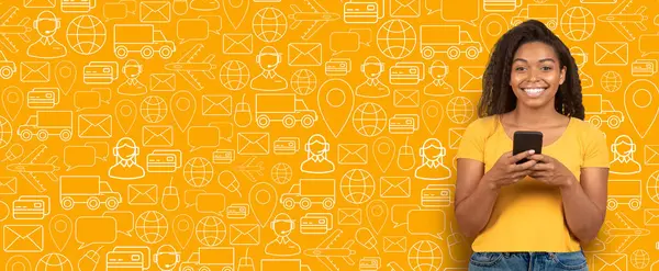 Neşeli bir alıcı canlı sarı bir arkaplan önünde duruyor, online alışveriş seçeneklerini keşfetmek için akıllı bir telefonla bağlanıyor, modern ticaret eğilimlerini vurguluyor.