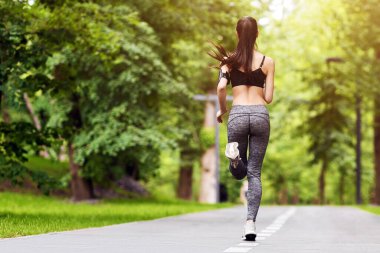 Spor motivasyonu. Sabah parkında koşan, dışarıda koşan, uzayı kopyalayan, formda bir kadının arka görüntüsü.