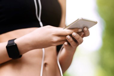 Fitness uygulaması. Açık havada antrenman yaparken spor etkinliğini izlemek için akıllı telefon uygulaması kullanan tanınmayan atlet kadın.