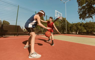 Açık sahada basketbol oynayan iki sporcu, boş alan. Panorama