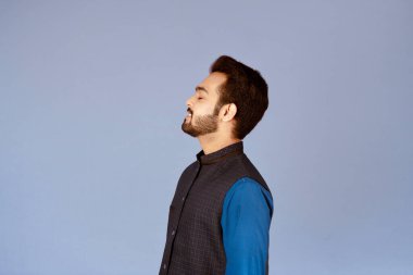 Kapalı gözlü barışçıl Hintli adamın yan görüntüsü eflatun arka planda rahatlıyor.