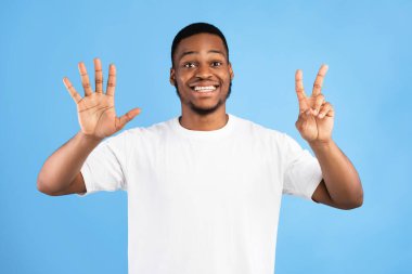 Siyah Adam, Yedi Numara, Mavi Arkaplanda Gülümseyen Kamera Pozu Veriyor. Stüdyo Çekimi