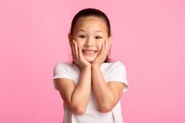 Vay canına. Yanaklarına dokunan heyecanlı Asyalı çocuğun yakın plan portresi. Pastel mor stüdyo duvarı üzerinde izole edilmiş.