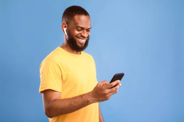 Cep telefonuyla kulaklık takan, müzik dinleyen, görüntülü sohbet yapan ya da mavi stüdyo arka planında iş görüşmesi yapan mutlu bir Afrikalı genç. Uzak iletişim