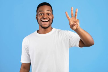 Üç Numara. Afro-Amerikalı Adam Mavi Arkaplanda Üç Parmak Sayıyor. Stüdyo Arkaplanı