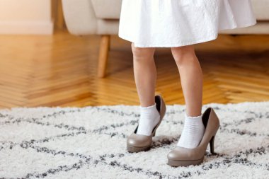 Evde oynayan yüksek topuklu ayakkabı giyen güzel küçük bir kız. Çocuklar Moda, Kıyafet ve Moda Konsepti