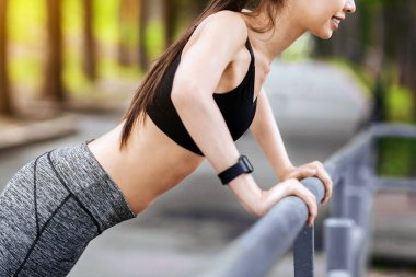 Asyalı fitness kızı göğüs ve kollar için şınav çekiyor, dışarıda tırabzan var, parkta antrenmanların keyfini çıkarıyor, fotokopi alanı ile yan görüş.