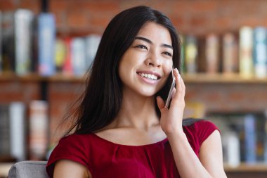 Modern Freelance. Cep telefonuyla konuşan rahat Asyalı kız ve kafede dizüstü bilgisayarda çalışmak.
