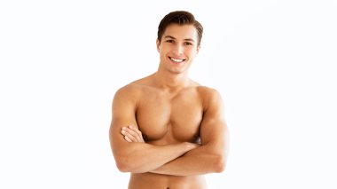 Kendine güvenen zinde adam. Çekici kaslı erkek portresi çıplak gövdeli ve pürüzsüz derili kolları çapraz duran, beyaz arka planda izole edilmiş. Stüdyoda poz veren gömleksiz adam, kameraya bakıyor.