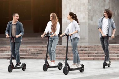 Şık İnsanlar Konsepti. Dört modaya uygun çok ırklı arkadaş birlikte vakit geçirir, stand-up scooterlara biner.