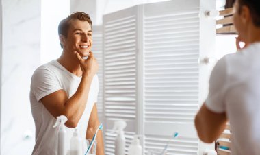 Güven kavramı. Neşeli adam tıraş olduktan ve aynaya baktıktan sonra çenesine dokunuyor.