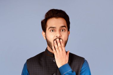 Sessizlik ya da hata konsepti. Şok olmuş Hintli adam, eli leylak arkaplanda ağzını kapatıyor.