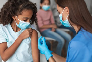 Çocuk aşısı. Hemşire, Siyah Prematüre Kız 'a şırınga enjekte ederek Covid-19' a karşı aşı yapıyor. Modern Klinikte Çocuk Bağışıklık Sistemi Aşılanıyor. Seçici Odaklanma