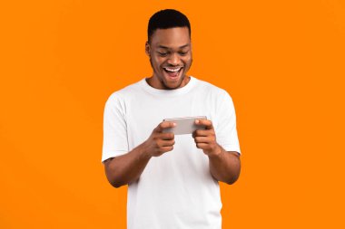 Sarı Stüdyo Arkaplan 'da Smartphone' da Heyecanlı Siyah Adam Oyunları Oynuyor. Mobil Oyun Konsepti